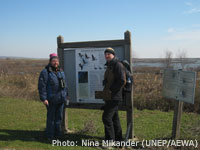 Yannis Tsougrakis (Birdlife Greece) and Petteri Tolvanen (WWF Finland) stand next to the sign funded by the previous LIFE project highlighting the look-alike problem between Greater White-fronted and Lesser White-fronted Geese / Photo: Nina Mikander (UNEP/AEWA)